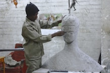 A sculptor works in his studio sculpting a large white body and head