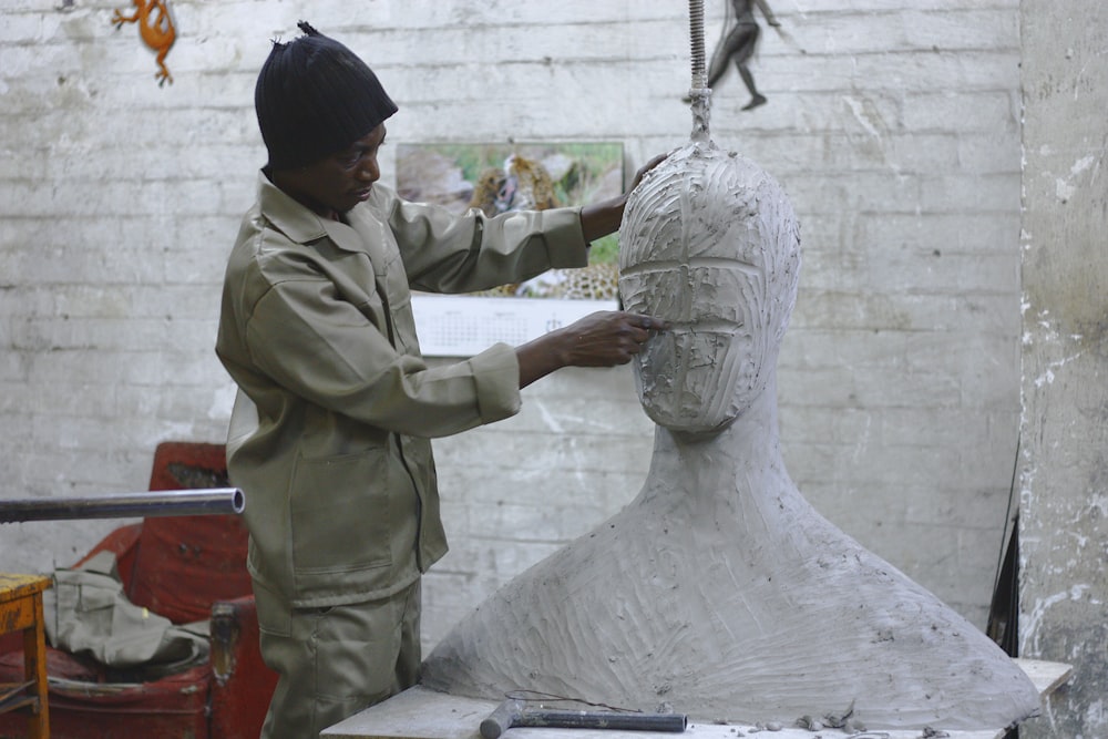 Ein Bildhauer arbeitet in seinem Atelier und modelliert einen großen weißen Körper und Kopf