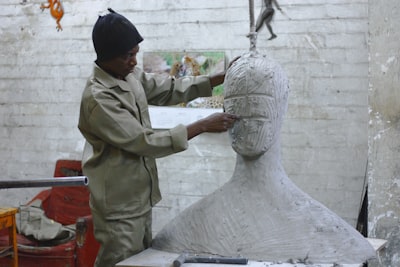 a sculptor works in his studio sculpting a large white body and head carve google meet background