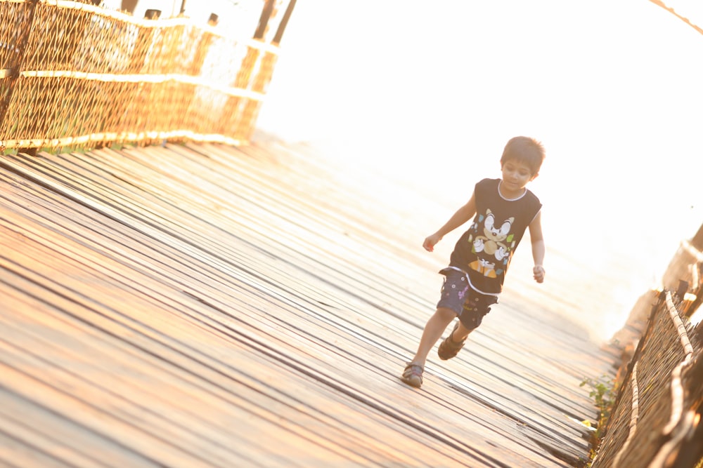 boy walking on brown wooden bridge