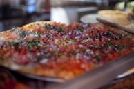 A colorful display of our weekly special pizza topped with fresh herbs.