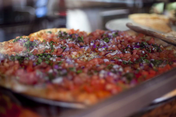 Artistic shot of a pizza topped with colorful vegetables and herbs, highlighting freshness