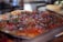 A close-up view of a pizza topped with fresh diced tomatoes, red onions, and chopped herbs, likely cilantro or parsley. The image captures the vibrant colors and texture of the ingredients, highlighting the freshness of the toppings.