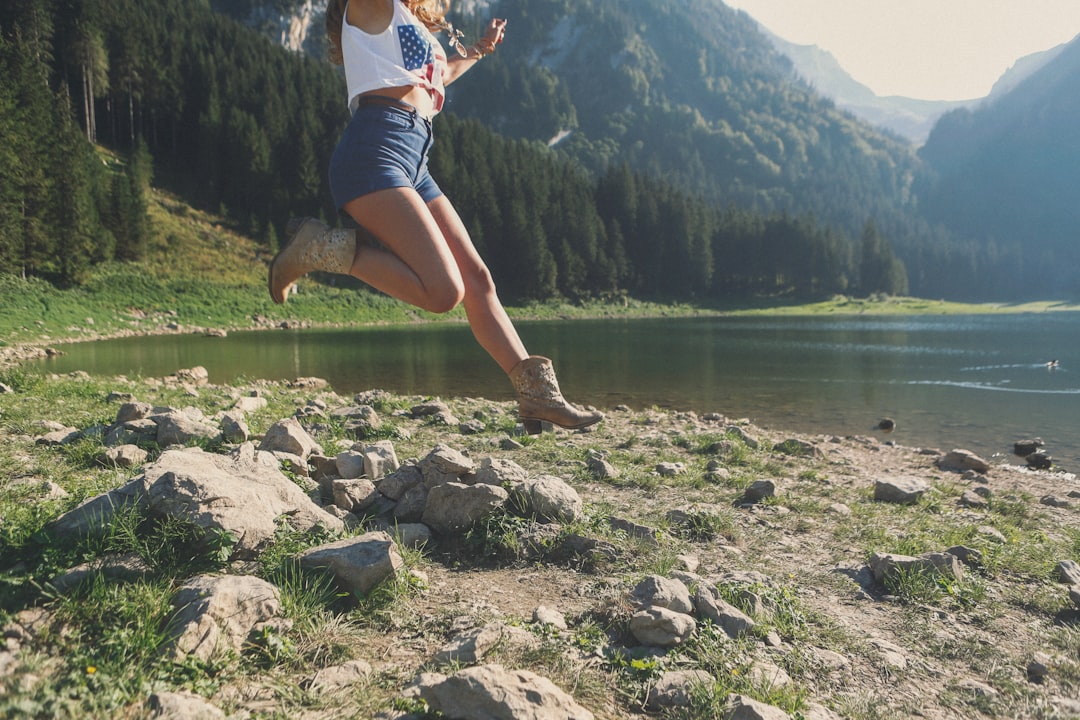 woman jumping near river, Leaping woman by a lake