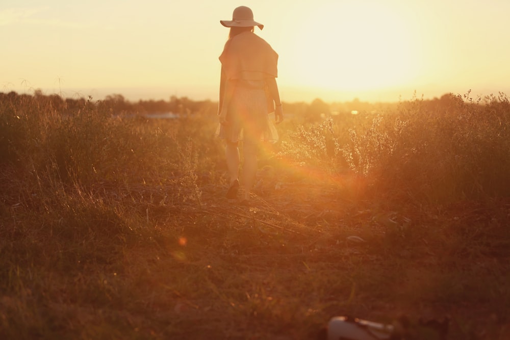 person standing on green grass during sunset