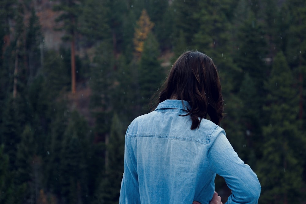 woman facing pine trees