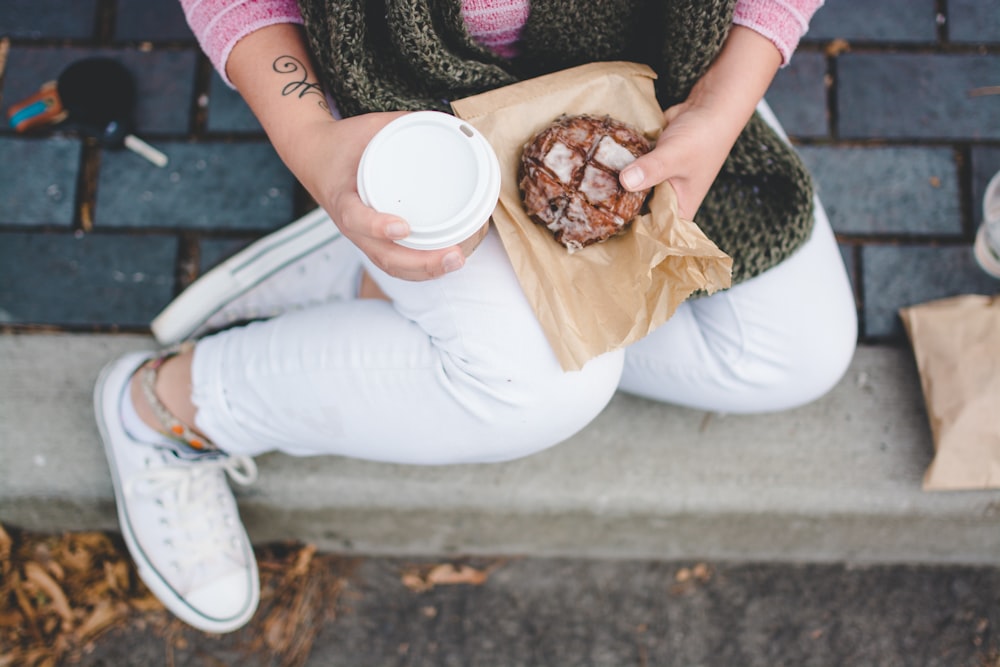 person sitting while holding white tumbler