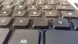 Close-up of a laptop keyboard being wiped down with a soft cloth to remove dust and smudges.