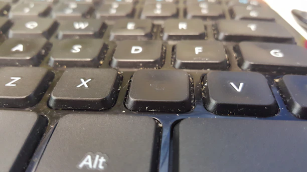 Close-up of a portable vacuum cleaner cleaning a computer keyboard with precision.