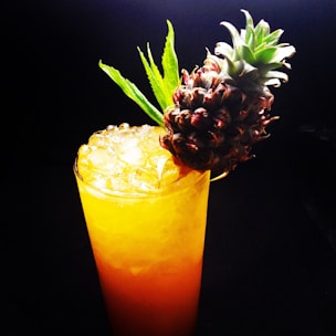 A colorful glass of freshly squeezed tropical fruit juice with ice cubes.