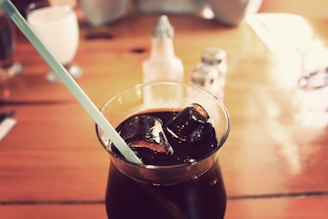 Refreshing soda with ice and a straw on a wooden table.