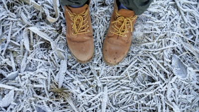 person wearing brown leather work boots icy teams background
