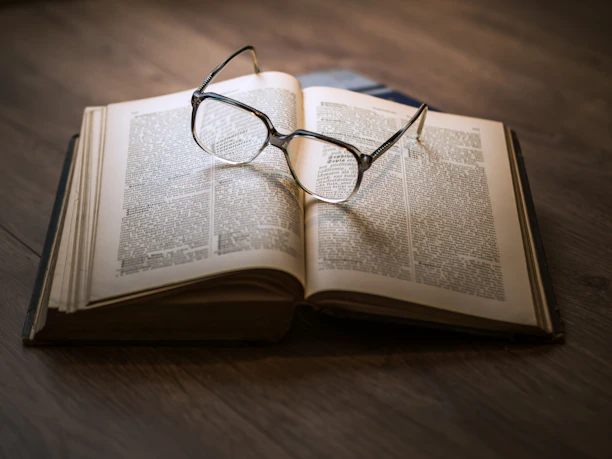 An open book with highlighted passages and a pair of reading glasses resting on top.
