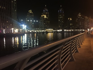 Nighttime scene of Geneva’s lakeside promenade illuminated with festive lights reflecting on the water.