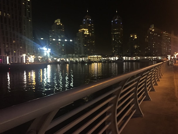 Nighttime scene of Geneva’s lakeside promenade illuminated with festive lights reflecting on the water.