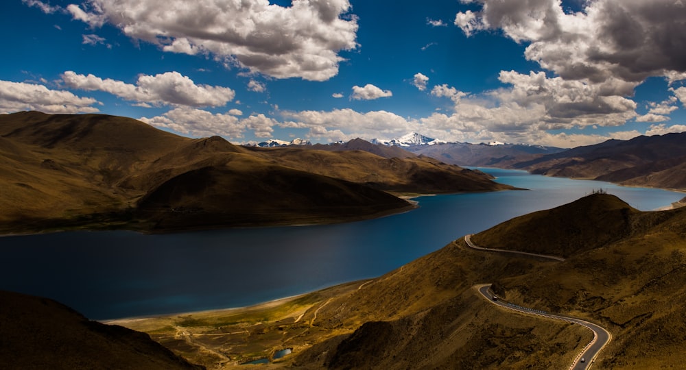 foto aérea da estrada em uma distância do lago e da montanha