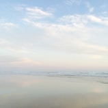 A tranquil beach scene with gentle waves and a pastel sunset sky.