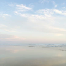 A soft, sunlit beach with gentle waves and pastel skies evoking tranquility