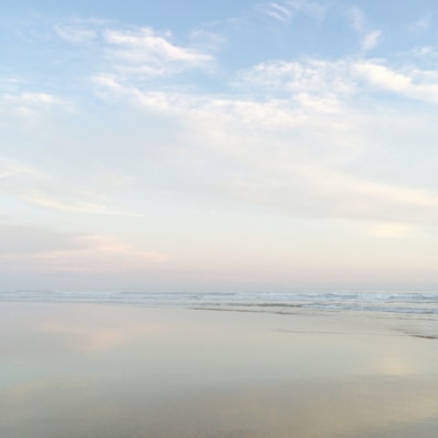A tranquil beach scene with gentle waves and a pastel sunset sky.