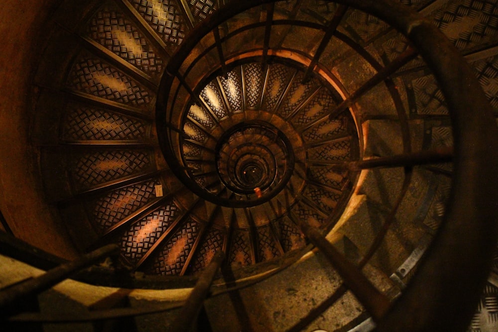 A worn spiral staircase with dark wood and faded designs