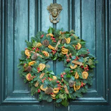 A festive floral wreath with bright orange and yellow blossoms hanging on a door.