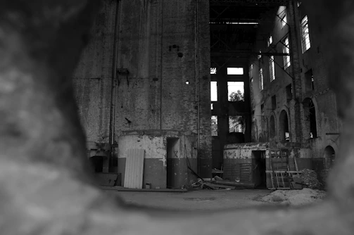 Black and white photograph capturing shadows and textures of abandoned buildings.
