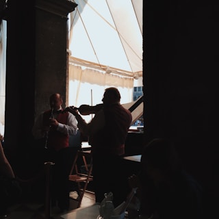 The guitarist and violinist performing together under soft, amber lighting at a classy reception.