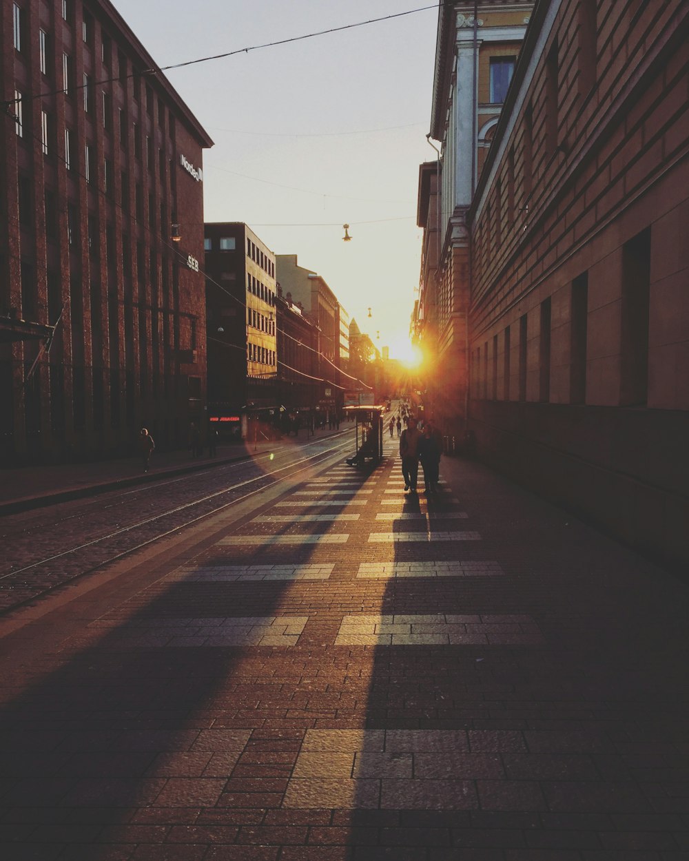 two person walking between concrete buildings