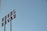 A metal sign with the letters oriented vertically against a clear blue sky. The letters appear to be arranged in an industrial style, attached to tall poles, suggesting a retro or vintage aesthetic.
