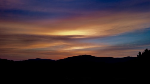 A serene landscape artwork showing a blend of vivid colors capturing a sunset over hills.