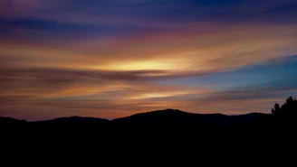 A serene landscape painting capturing a sunset over rolling hills.
