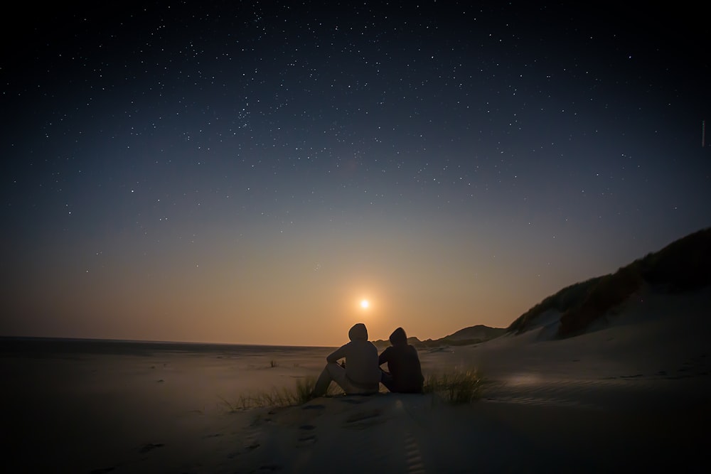 silhouette of two person sitting during golden hour