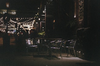 A cozy outdoor seating area at Wrangler Snack Bar with warm evening lights and a street view.