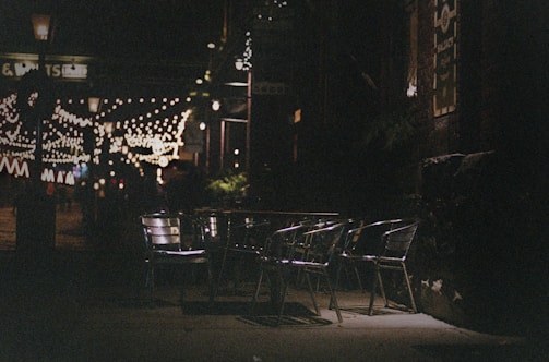A cozy outdoor seating area at Wrangler Snack Bar with warm evening lights and a street view.