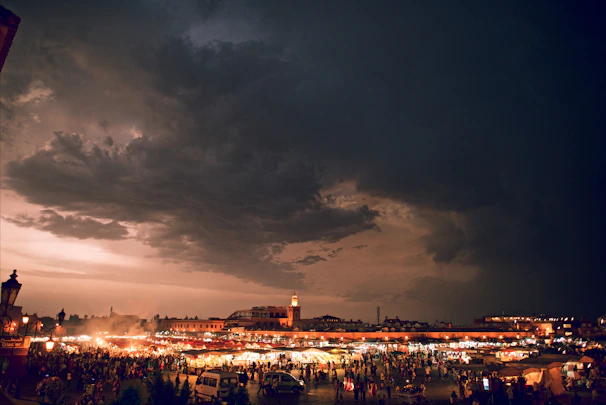 A vibrant scene of a mystical marketplace filled with shadowy figures and glowing artifacts under a violet sky.
