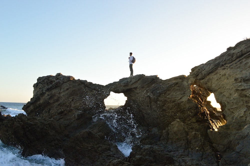 man standing on brown rock formations