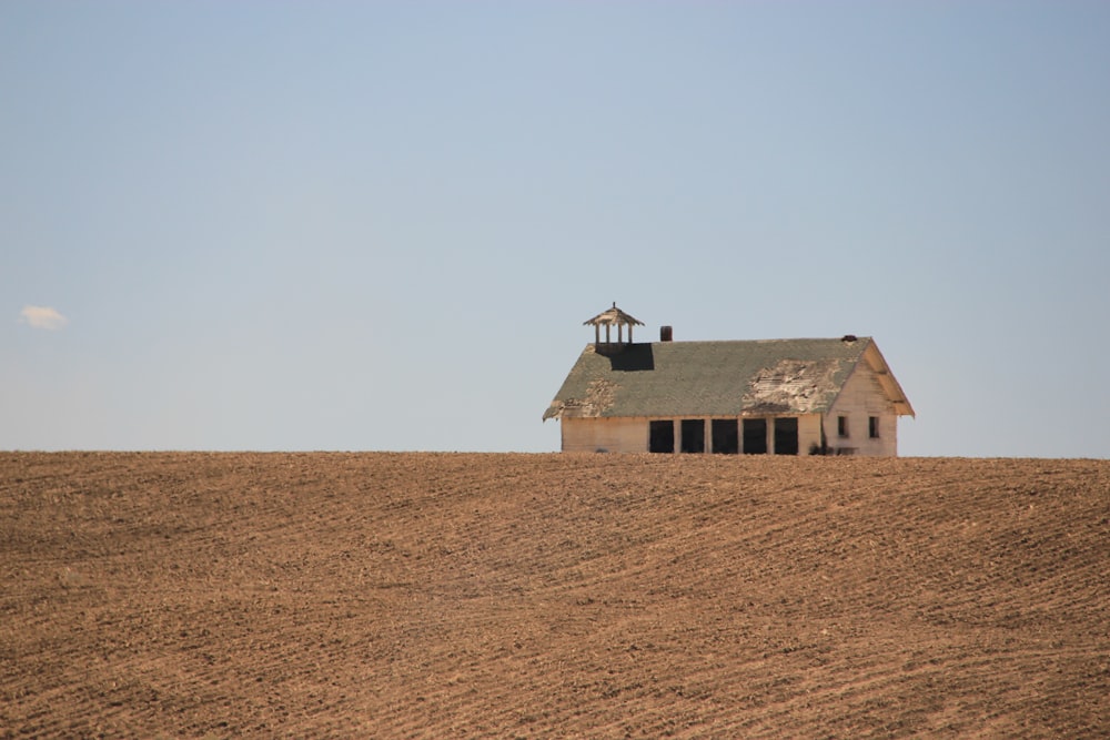 Casa marrón y blanca en campo marrón bajo cielo gris