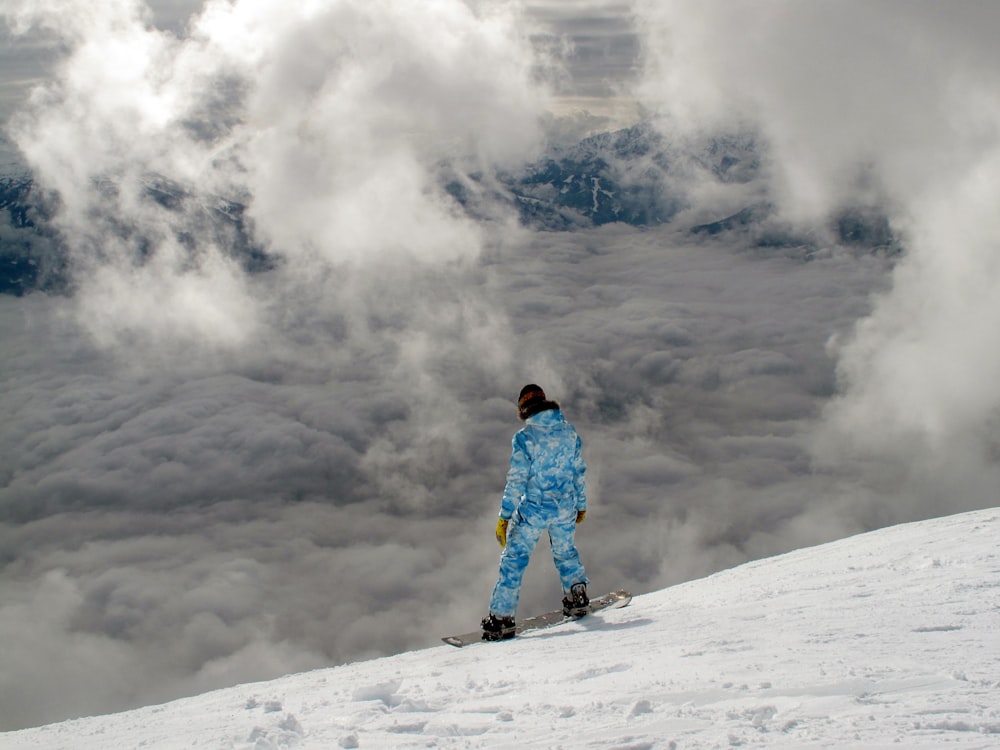 A snowboarder overlooking a cloudy and snow covered hill