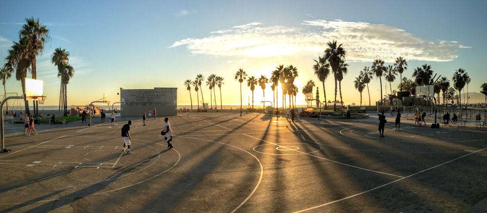 pessoas jogando basquete na quadra durante o pôr do sol