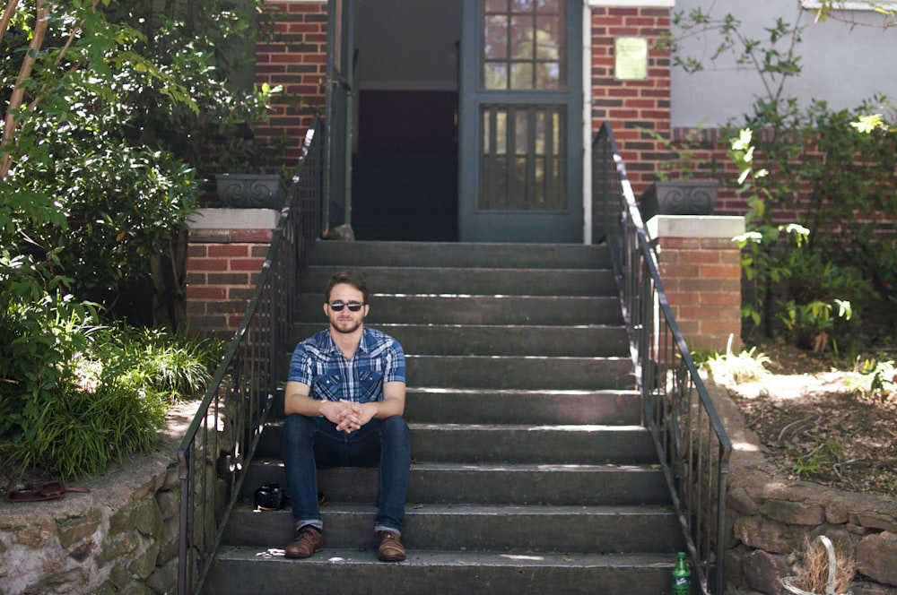 man in blue and white shirt sitting on stair