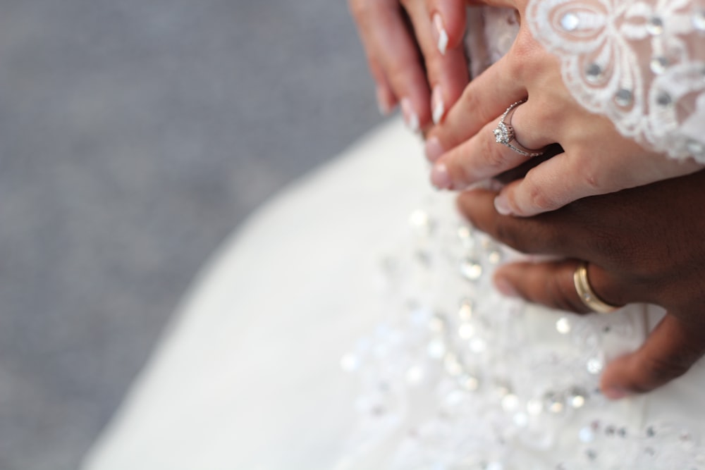 people holding hands while wearing gold-colored wedding rings