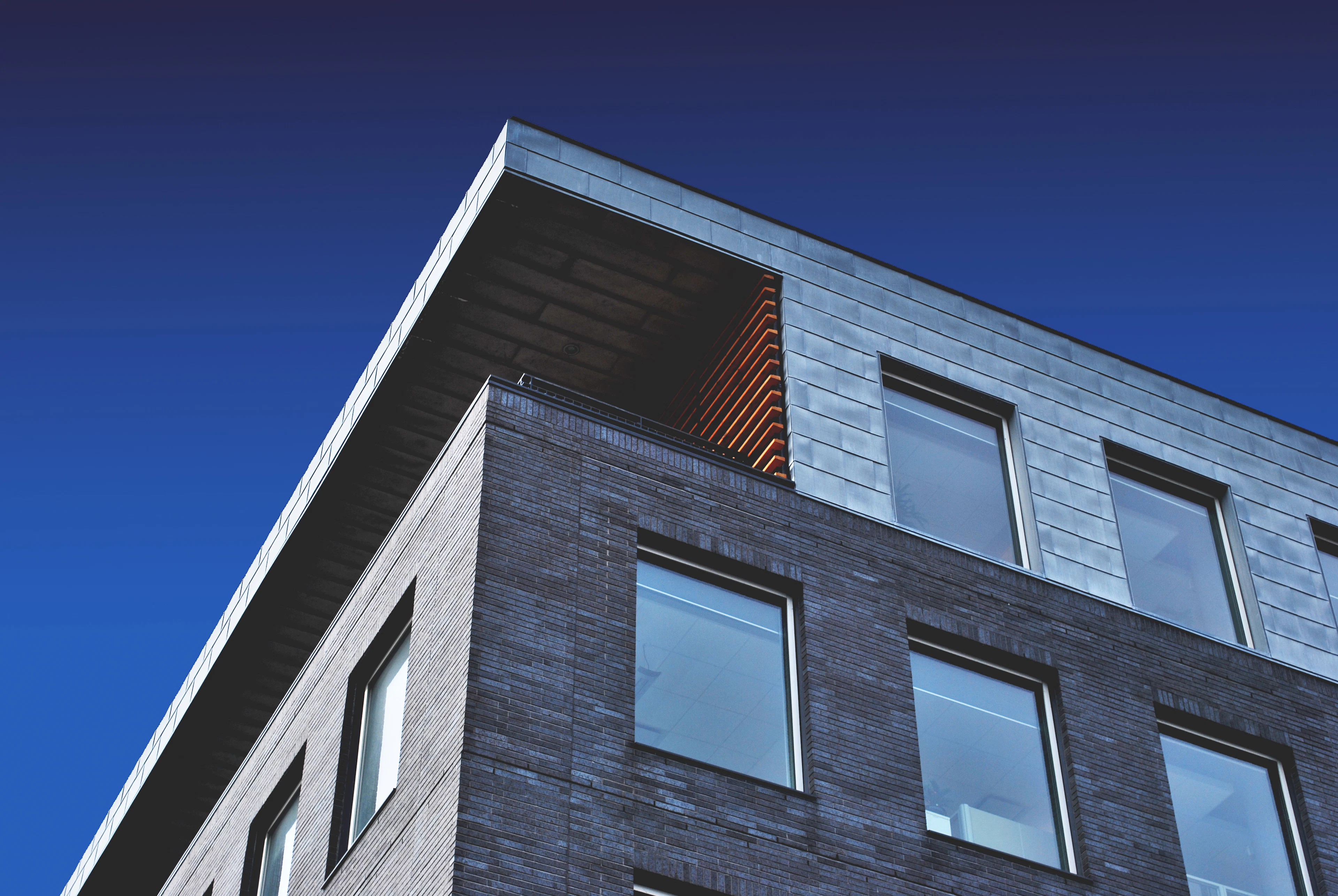 Modern dark-stone residential tower under a deep blue sky