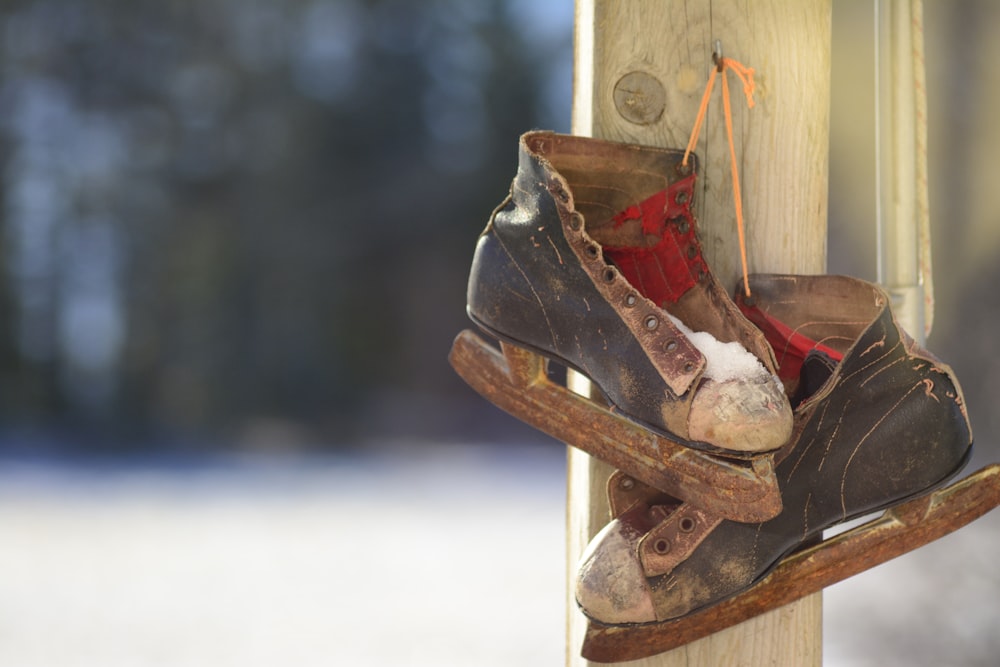 pair of black-and-brown ice skates hanging on brown wooden post