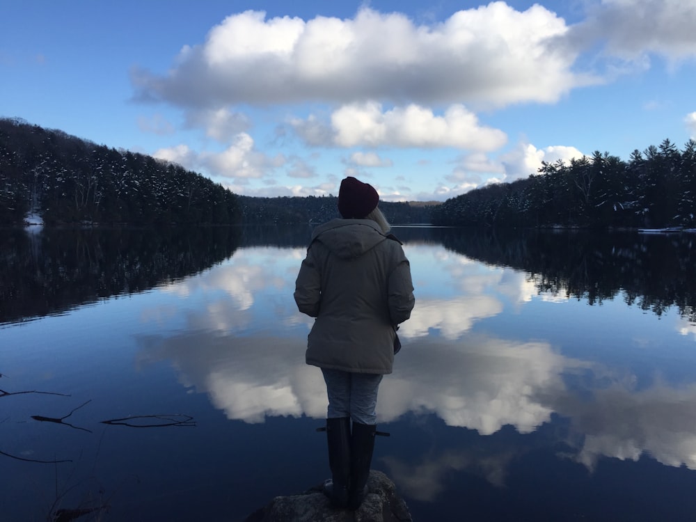 person in gray hoodie in front of body of water