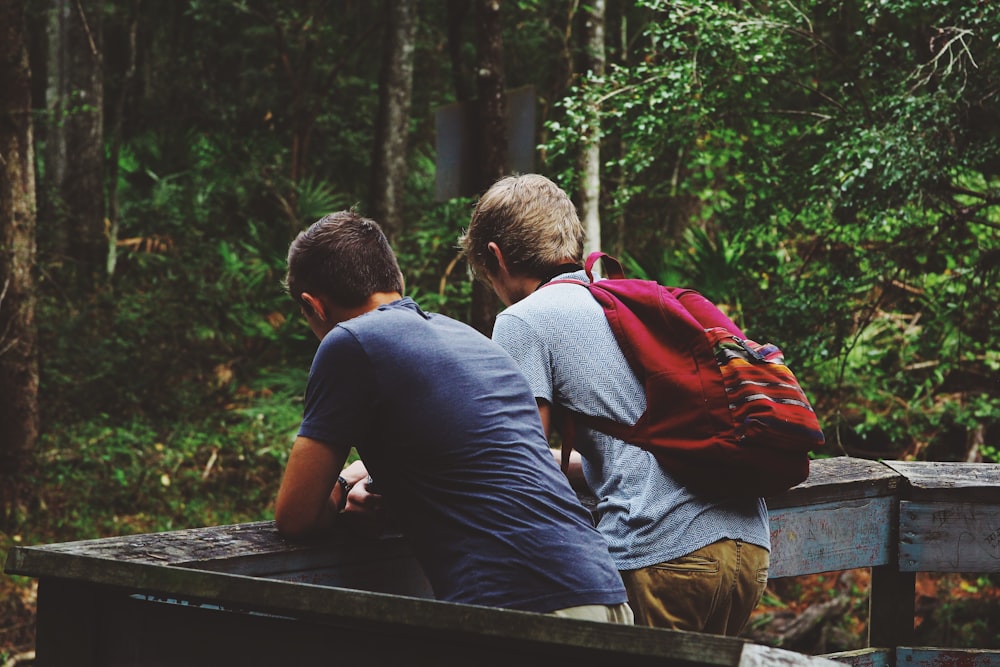 two men leaning on fence