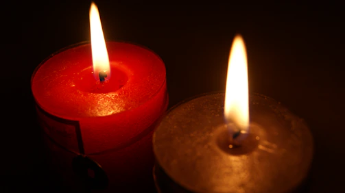 Soft red and white candles lit together symbolizing comfort and solidarity.