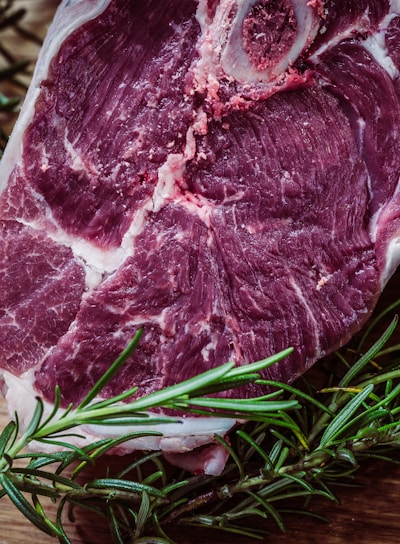 raw meat and green leaf plant on brown surface