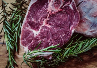 raw meat and green leaf plant on brown surface