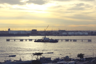 Oil and gas storage tanks reflecting the sunset over the horizon at a maritime port.