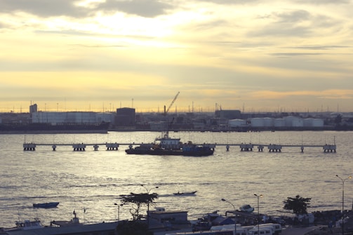 Oil and gas storage tanks reflecting the sunset over the horizon at a maritime port.